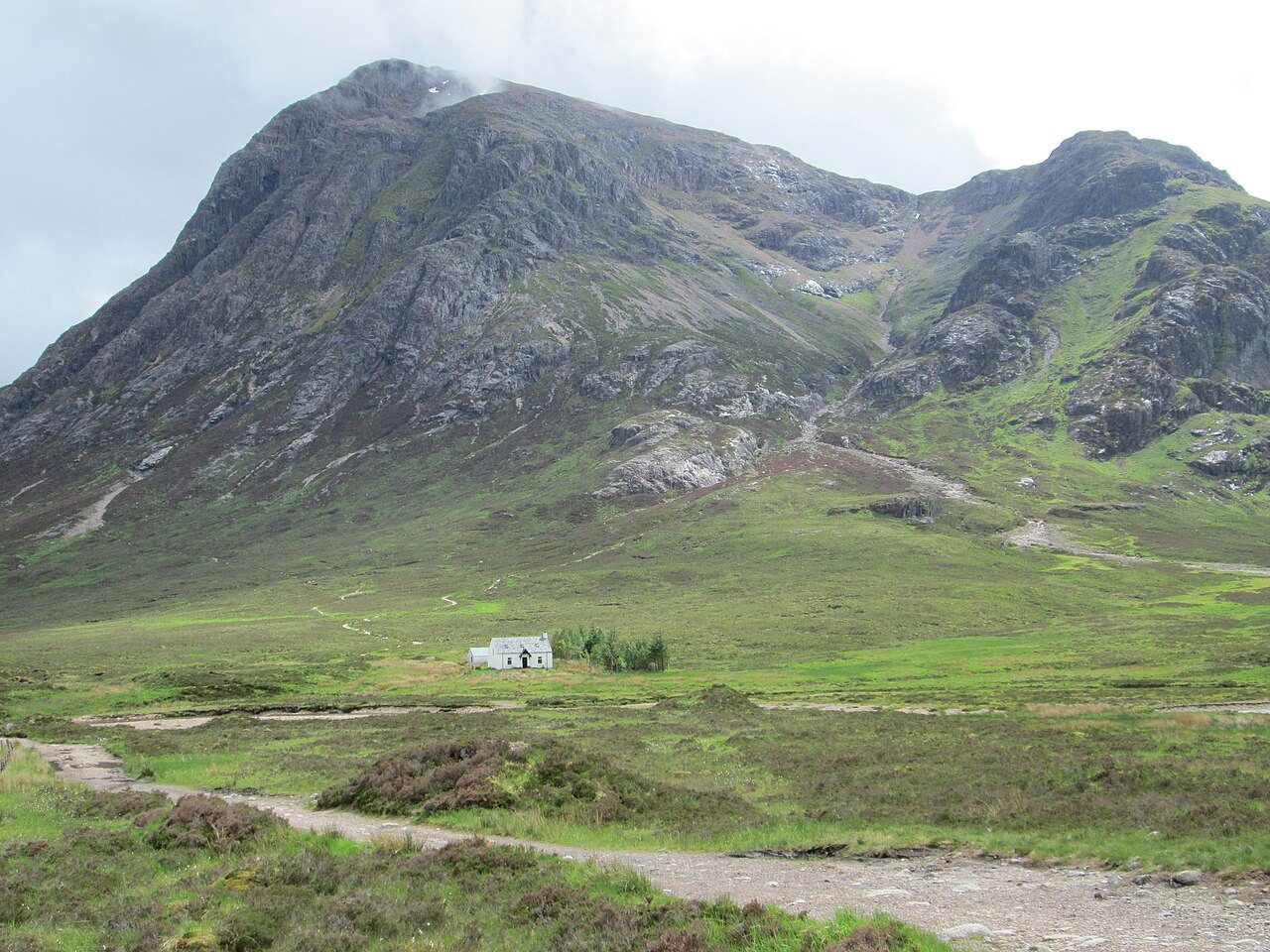 A steep mountain above a white cottage in Glencoe